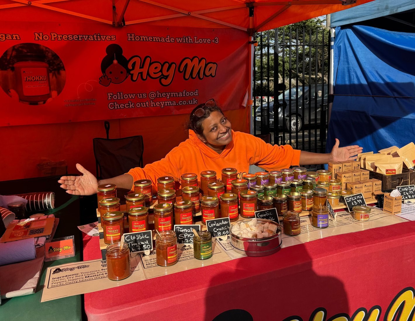 Hema smiling behind her Hey Ma market stall full of thokku jars